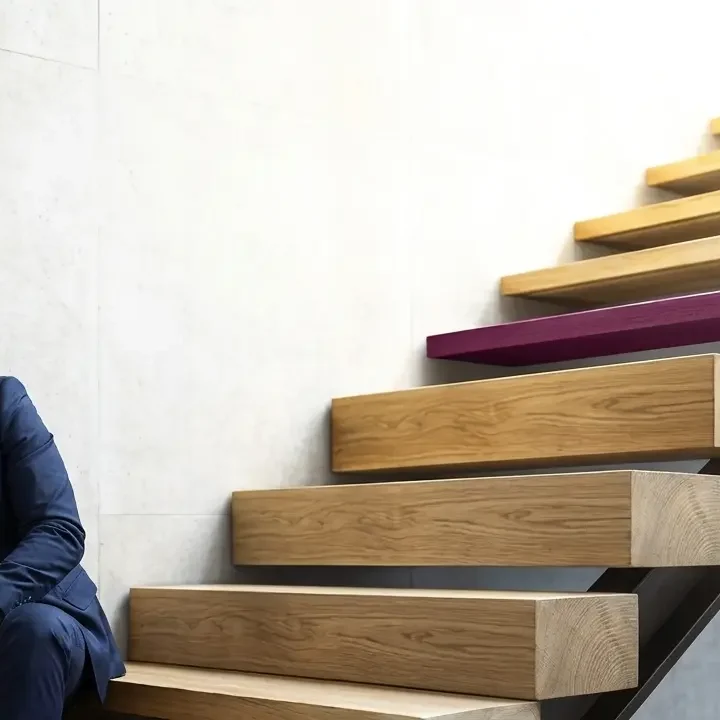 Signe d'épuisement : un dirigeant assis au pied de l'escalier. La fatigue décisionnelle l'empêche d'avancer et de trouver la solution.